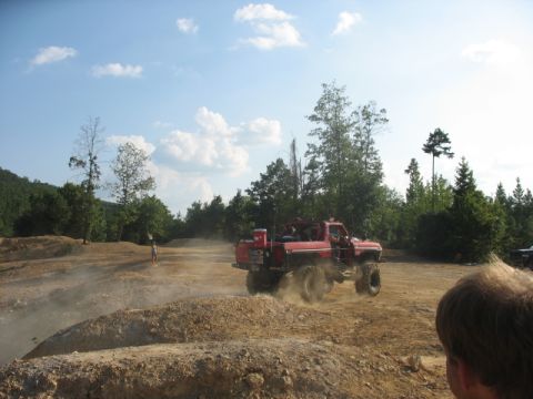1979 Ford Bronco - A red off-road truck navigates a dusty track at an off-road park.