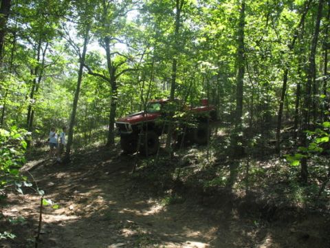 1979 Ford Bronco - Red 1979 Ford Bronco navigates a dirt path through a dense forest.
