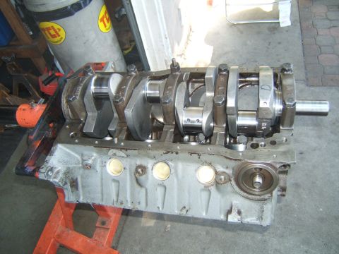 1988 Ford Bronco - A V8 engine's crankshaft and connecting rods are assembled within the engine block, resting on an orange engine stand.