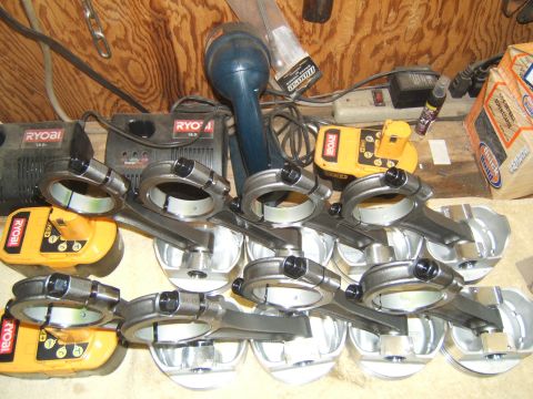 1988 Ford Bronco - Engine pistons and connecting rods are laid out with Ryobi battery chargers in the background.