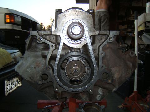 1988 Ford Bronco - Engine block assembly with timing chain and gears, partially obscuring a white van in the background.