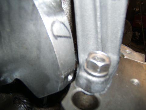 1988 Ford Bronco - Engine bay close-up showing a heat shield marked with a handwritten D and a hex bolt beside the bell housing.