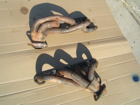 1988 Ford Bronco - Two exhaust manifolds, likely for a V8 engine, are shown laid out on a surface.