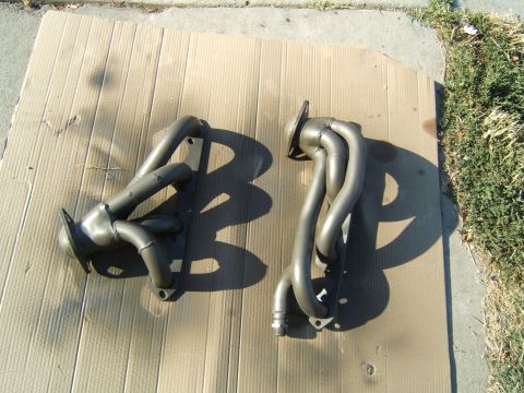 1988 Ford Bronco - Pair of exhaust headers shown on a cardboard surface outdoors.