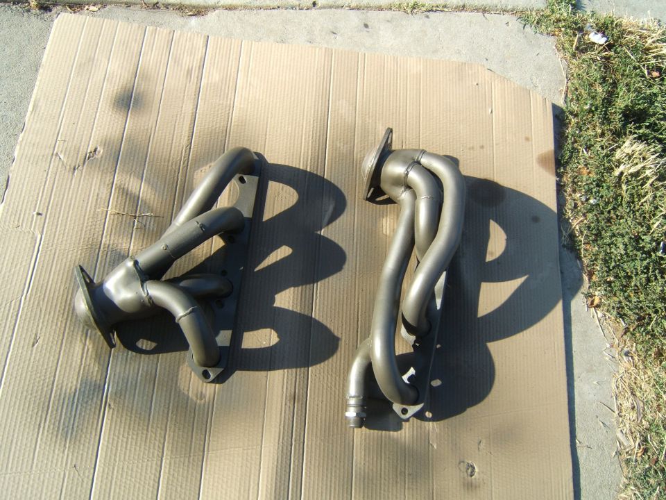 Two exhaust headers, one on the left and one on the right, laid out on cardboard