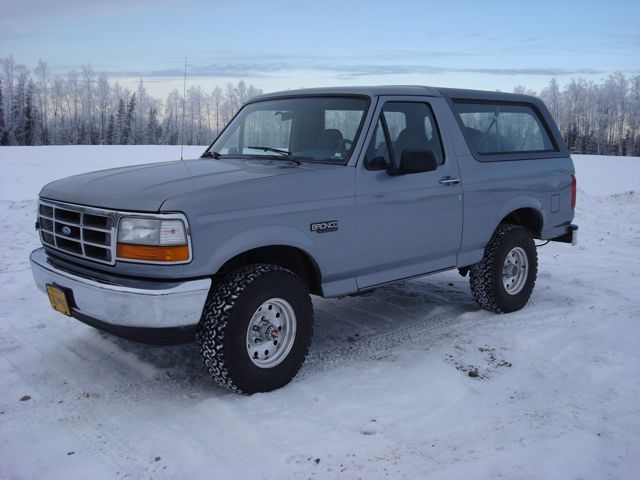 1994 Ford Bronco parked in a snowy field with trees in the background