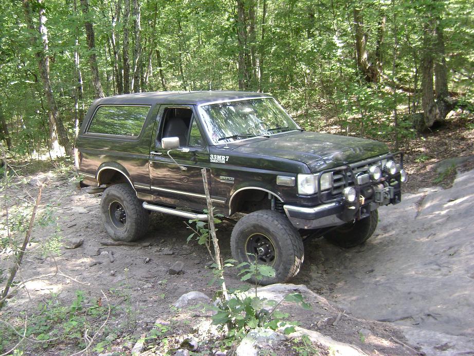 Black Ford Bronco with off-road tires and auxiliary lights on a dirt trail