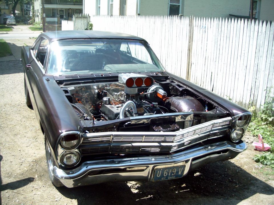 Front view of a dark purple car with hood open, showing a large engine with a scoop. License plate reads U 619 V