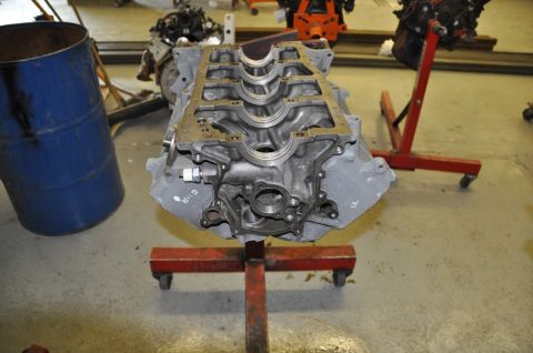 1996 Ford Bronco - Engine block on a stand in a workshop environment with a blue barrel nearby.
