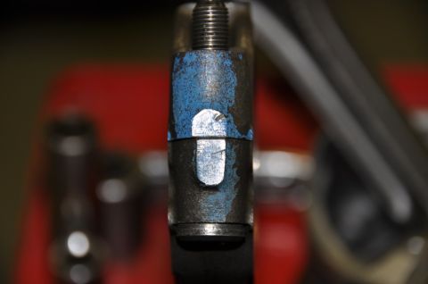 1996 Ford Bronco - A close-up view of a metal bolt with blue paint markings and a silver nut.