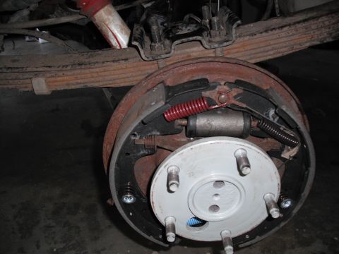 1991 Ford Bronco - Close-up of a vehicle's rear drum brake assembly, showing brake shoes, springs, and wheel cylinder.