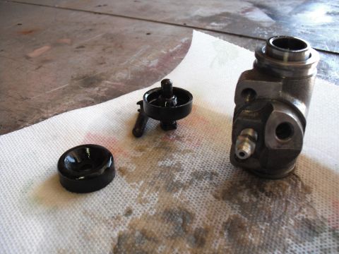 1991 Ford Bronco - Disassembled brake master cylinder components resting on paper towels with fluid stains.