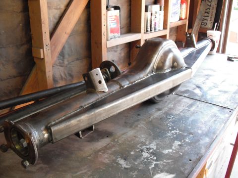 1991 Ford Bronco - Custom rear axle assembly with fabricated housing and differential cover, resting on a workbench.
