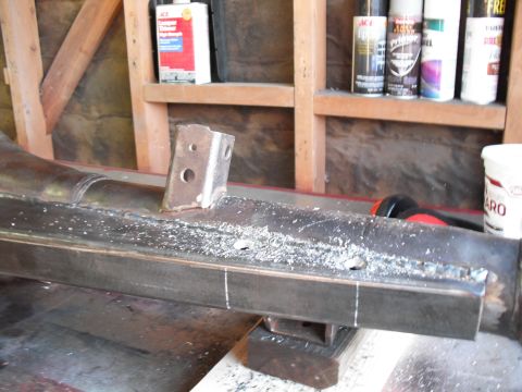 1991 Ford Bronco - A metal bracket is welded onto a frame, with metal shavings scattered around the work area.