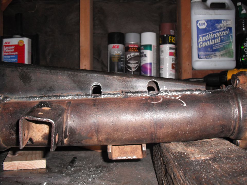Axle tube with plate truss stitch-welded on, rosette holes and bracket, on a bench
