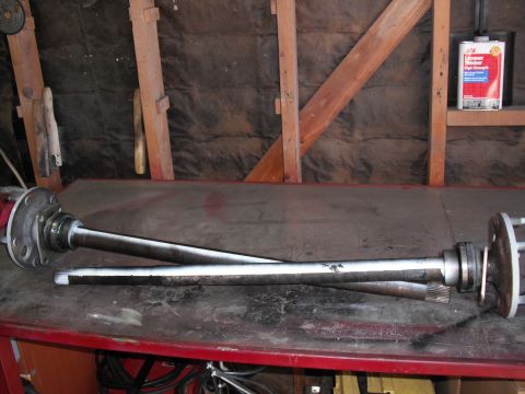 1991 Ford Bronco - Two axle shafts are laid out on a red-topped workbench, possibly for installation or repair.