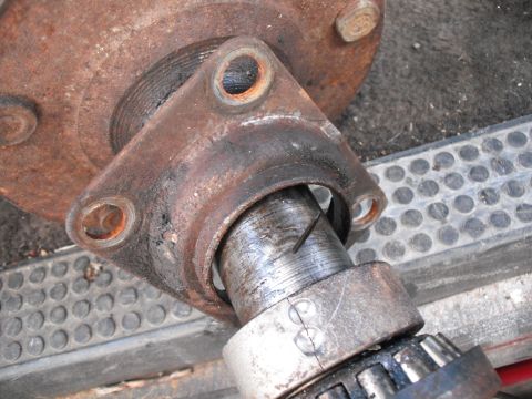 1991 Ford Bronco - A close-up view of a rusted axle component, showing a bearing and mounting holes, likely part of a vehicle's drivetrain.