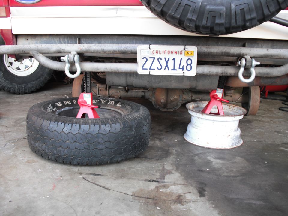 Red and white Ford SUV on jack stands with tube bumper, spare tire and CA plate 2ZSX148
