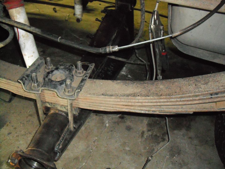 Leaf spring pack U-bolted to a rear axle tube seen from under the truck