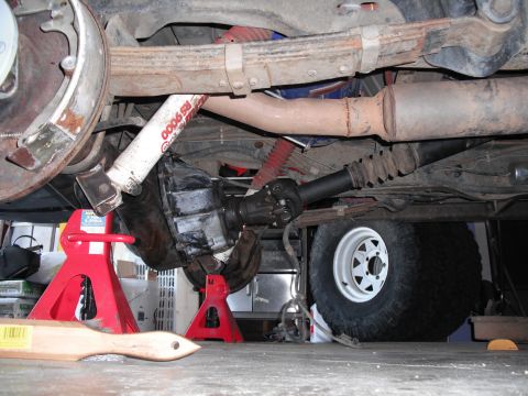 1991 Ford Bronco - The rear axle and suspension components of a vehicle are shown, supported by red jack stands.