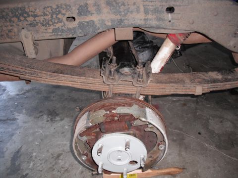 1991 Ford Bronco - Close-up view of a vehicle's rear axle drum brake assembly and leaf springs.