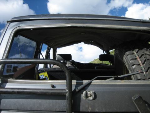 1978 Ford Bronco - The interior of an off-road vehicle is seen through the open rear window, with a spare tire mounted inside.