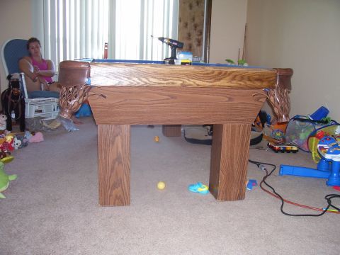 1991 Ford Bronco - A pool table is the central focus of this indoor scene, with a woman seated nearby and toys strewn across the carpet.