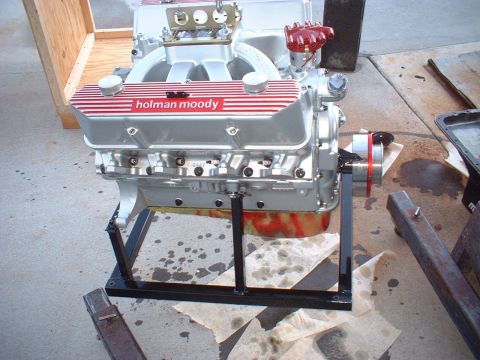 1969 Mercury Cyclone - A Holman Moody V8 engine is displayed on a black stand, showing its silver block and red-striped valve covers.