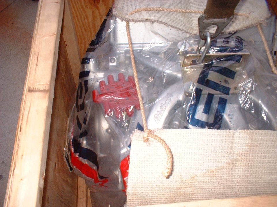 Engine part in crate with red component and blue lettering