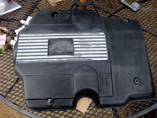 Black plastic finned engine cover with masked center on a patio table