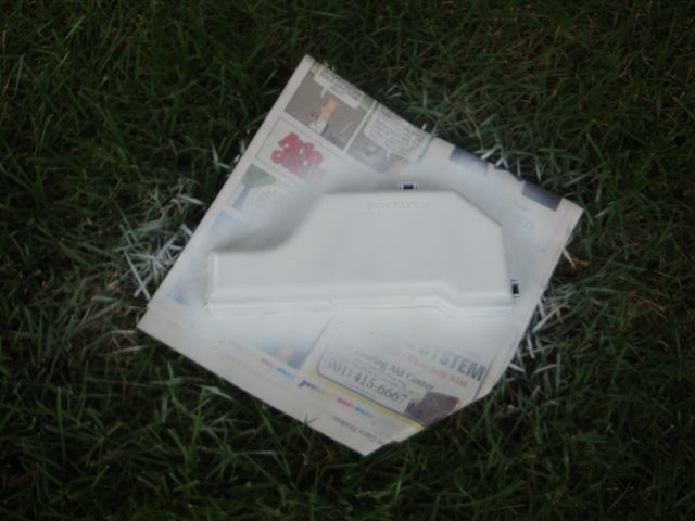 White painted plastic reservoir or cover drying on newspaper in grass