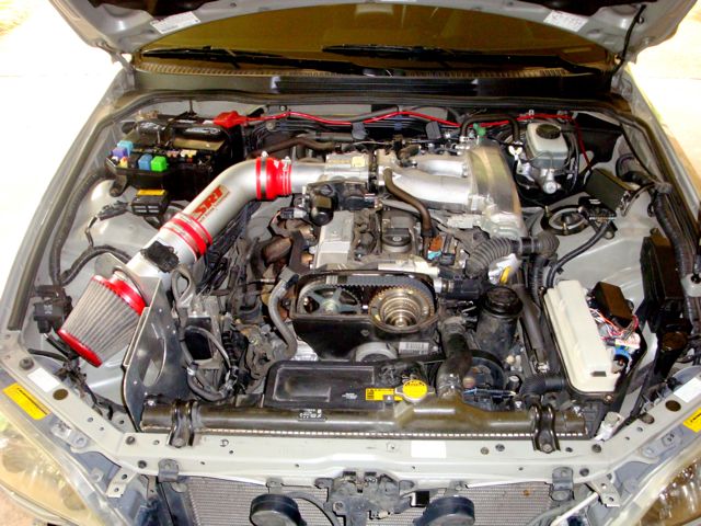 Inline-six engine bay with polished cold air intake, red cone filter and strut brace