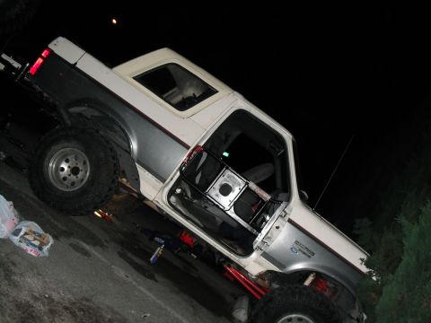 1991 Ford Bronco - A lifted Ford Bronco is parked at night with its driver's side door open.