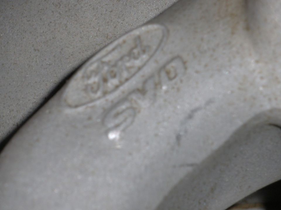Close-up of a cast metal part showing the Ford logo and some casting numbers