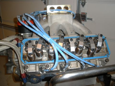 1995 Ford Bronco - This is a close-up view of a V8 engine's valve cover and intake manifold, blue spark plug wires.