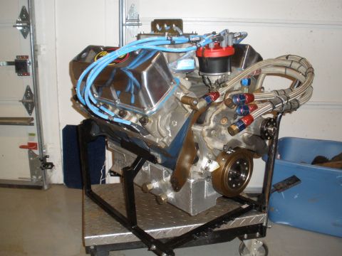 1995 Ford Bronco - A V8 engine, likely a performance build, is displayed on a metal stand in a garage setting.