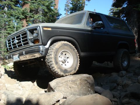 1984 Ford Bronco - Ford Bronco tackling a challenging off-road trail with large rocks.