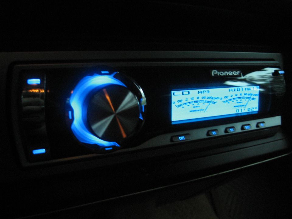Pioneer car stereo with blue illuminated ring and digital display showing MP3 information