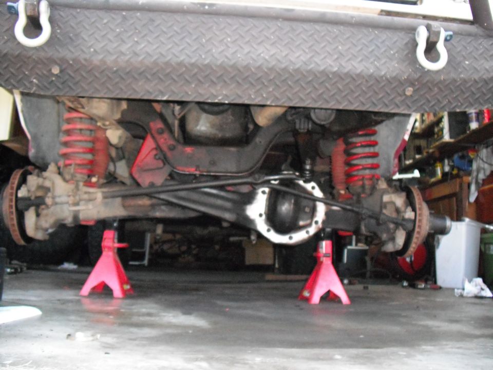 Undercarriage view of a vehicle's front axle and suspension on jack stands