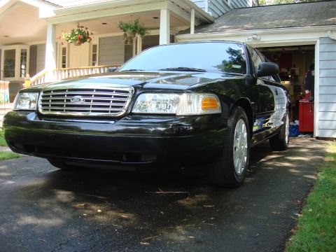 2006 Ford Crown Victoria - Front view of a black 2006 Ford Crown Victoria parked in front of a house and garage.