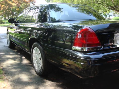 2006 Ford Crown Victoria - Rear passenger side view of a black sedan parked on a residential street.
