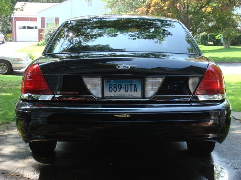 2006 Ford Crown Victoria - Rear view of a black 2006 Ford Crown Victoria, showing its taillights, Ford emblem, and license plate.