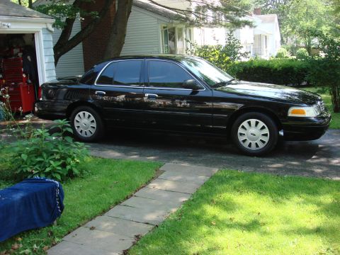 2006 Ford Crown Victoria - Side view of a black 2006 Ford Crown Victoria sedan parked in a residential driveway.