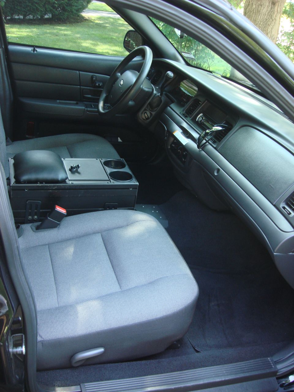Interior of a police car, showing front seats, dashboard, and center console with cup holders