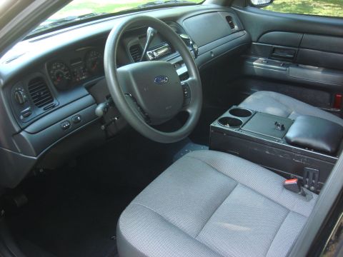 2006 Ford Crown Victoria - The interior of a police vehicle is shown, the dashboard, steering wheel, and a specialized center console.