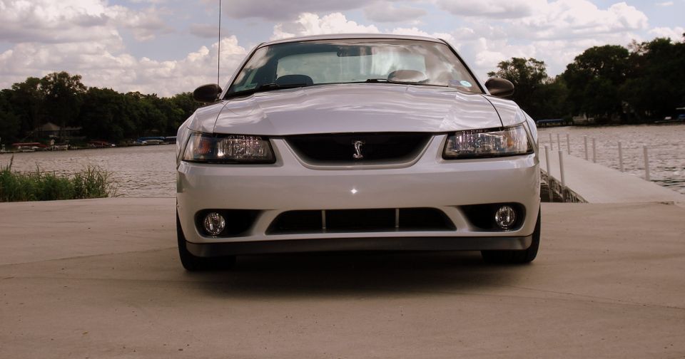 White 2001 Ford Mustang Cobra front view with a lake in the background