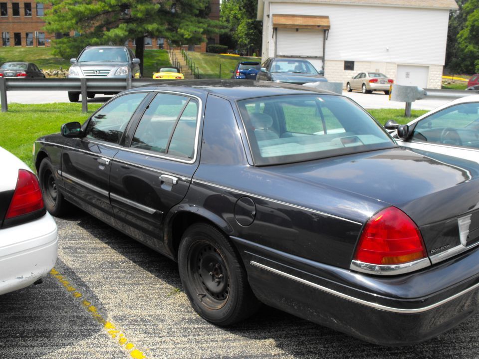 Black Ford Crown Victoria sedan, rear three-quarter view in a parking lot