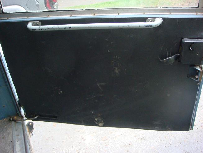 Interior door panel with grab handle and lock mechanism. Some scuff marks visible