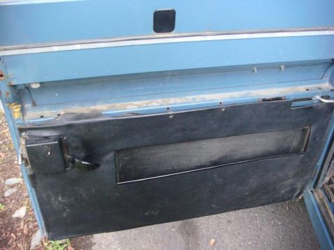 1972 Land Rover Land Rover - Close-up view of the interior door panel of a blue vehicle, showing the door handle and a black insert.