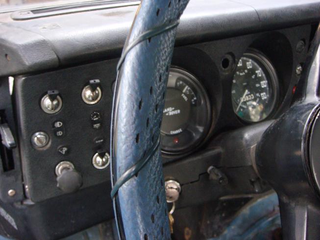 1972 Land Rover Land Rover interior showing dashboard gauges and switches. Steering wheel is wrapped in blue material